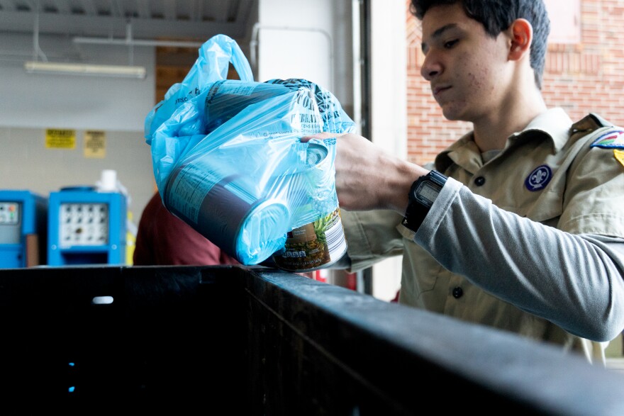 Scout Lucas Roa, 13, of Troop 21 empties a bag of canned goods, like green beans, into a sorting bin for the annual Scouting for Food event in Clayton, Mo. 