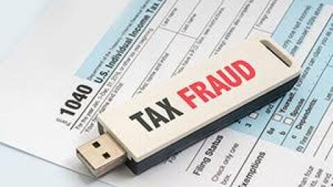 USB drive saying "tax fraud" on top of 1040 tax form