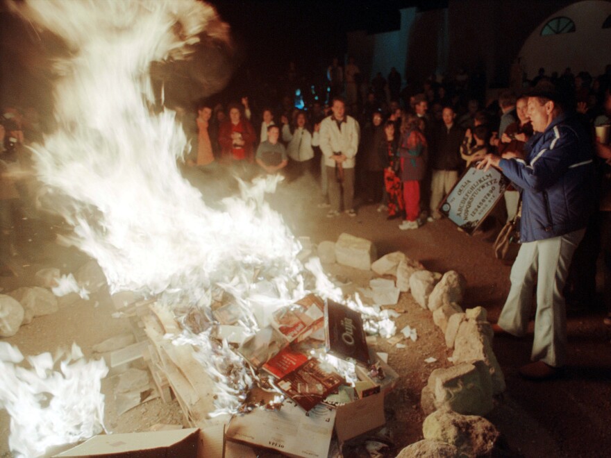 A woman tosses a Ouija Board into a bonfire outside a church in New Mexico in 2001, after  the church's pastor urged parishioners to burn dozens of Harry Potter books and other types of literature and games they found offensive.