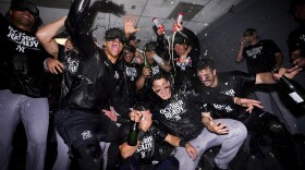 The New York Yankees celebrate clinching a playoff spot after a 2-1 win in 10 innings over the Seattle Mariners in a baseball game Wednesday, Sept. 18, 2024, in Seattle. (AP Photo/Lindsey Wasson)