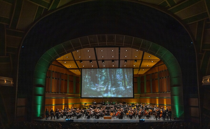 Scenes from Coos Bay, where Steve Prefontaine grew up running, play above the orchestra during the world premiere of Portland-based composer David Schiff’s PREFONTAINE.