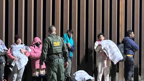 An unidentified Border Patrol agent speaks to migrants along the border fence where it meets Cocopah tribal land in Yuma County on Friday, Dec. 16, 2022.