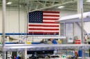 An employee stands in front of an American flag displayed at Zentech manufacturing in Bloomington.