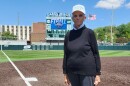 A woman poses for a photo on a softball field