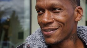 Closeup man's face, smiling lookng to side. Tattoo on neck