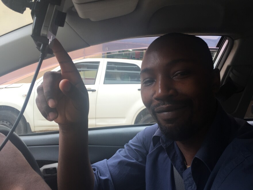 One of Uber's Nairobi drivers, Jackson Kamau, points proudly to an iPhone that shows his high rating.