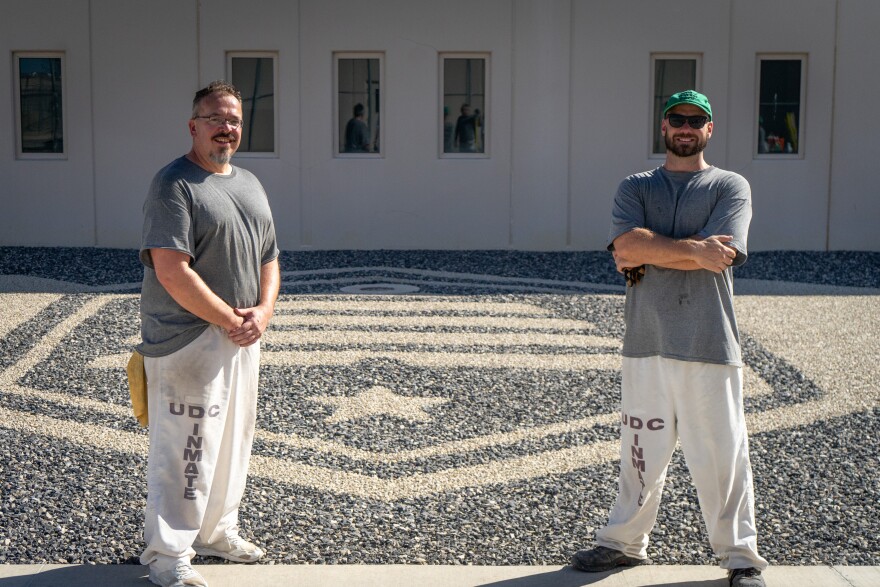 Ryan Parker and Alexander Wardell, inmates at the Utah State Correctional Facility in Salt Lake City, stand in front of gravel art recreating the state flag, Aug. 20, 2026.