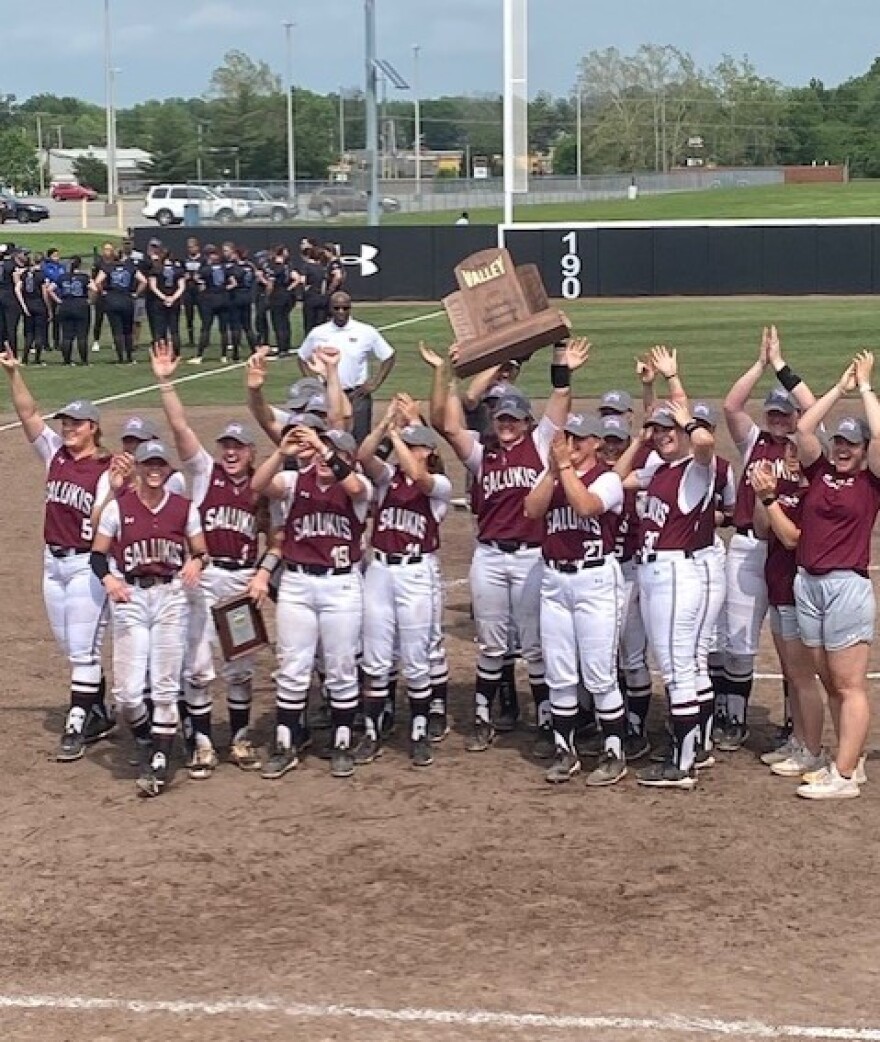 The SIU softball team holds the MVC Tournament trophy up for the crowd