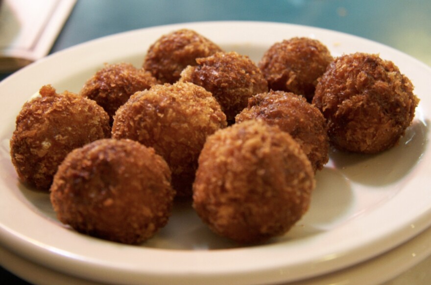 A close-up of golden fried croquetas balls on a white plate 