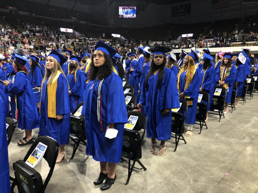 Students standing with cap and gown on. 