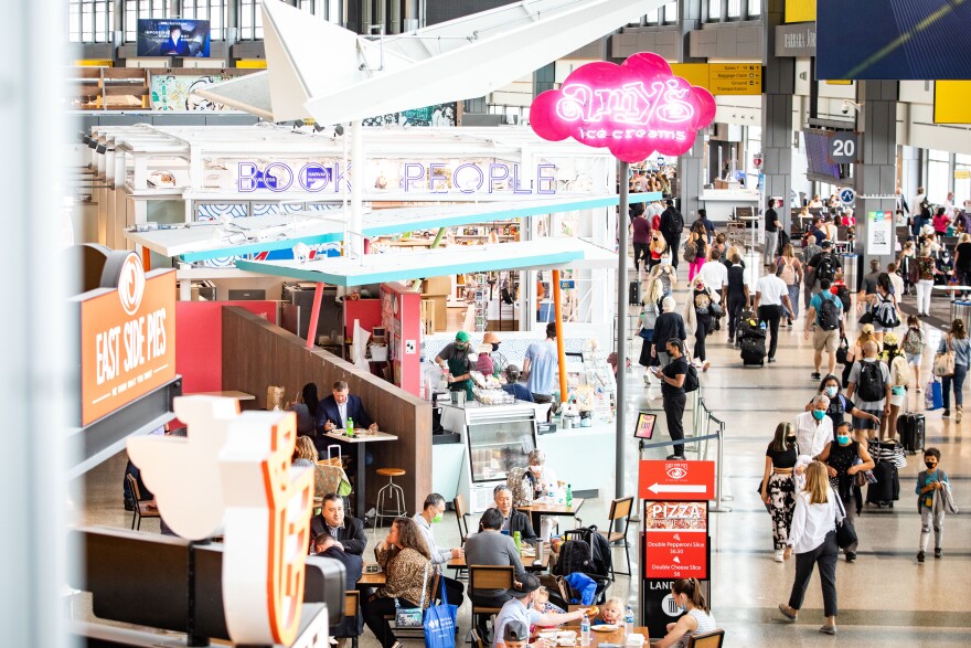Crowds of passengers, some wearing protective face masks, at restaurants at the food and dining concession area within the Austin-Bergstrom International Airport main terminal
