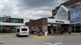 The main entrance of Carle BroMenn Medical Center showing a small passenger van parked outside and an enclosed walkway above adorned with a logo that reads 'Carle.'