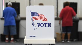 Tremain Davis, left, and his mother Vallire Davis, feed their ballots into the scanners at the Wyandotte County Election Office in Kansas City on Friday morning. Vallire said she brings her special needs 47-year-old son every election to help him cast his ballot.