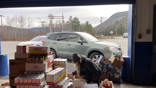 SNAP recipients line up at the New Hampshire Food Bank’s warehouse in Berlin, waiting for boxes of non-perishables and fresh produce. A New Hampshire Food Bank employee packs boxes for the people in line.