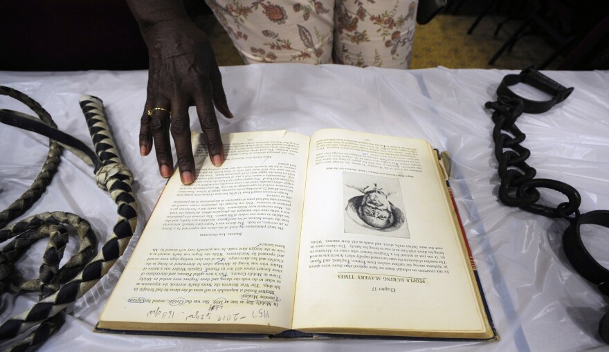 FILE - Barbara Martin looks at a display about slavery in Mobile, Ala., on Monday, Aug. 26, 2019. Republican Tommy Tuberville told people Saturday, Oct. 8, 2022, at an election rally in Nevada that Democrats support reparations for the descendants of enslaved people because “they think the people that do the crime are owed that.” His remarks cut deeply for some, especially in and around Africatown, a community in Mobile, Alabama, that was founded by descendants of Africans smuggled in 1860 to the United States aboard a schooner called the Clotilda. (AP Photo/Jay Reeves, File)