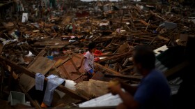 A girl crosses between collapsed roof tops in the damaged downtown area in Tacloban, Philippines, on Sunday.