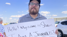 Source New Mexico Senior Reporter Shaun Griswold stands with a sign asking attendees to engage with him as a journalist after the Mark Ronchetti campaign denied him access to their event in Carlsbad, N.M., on Aug. 14, 2022.