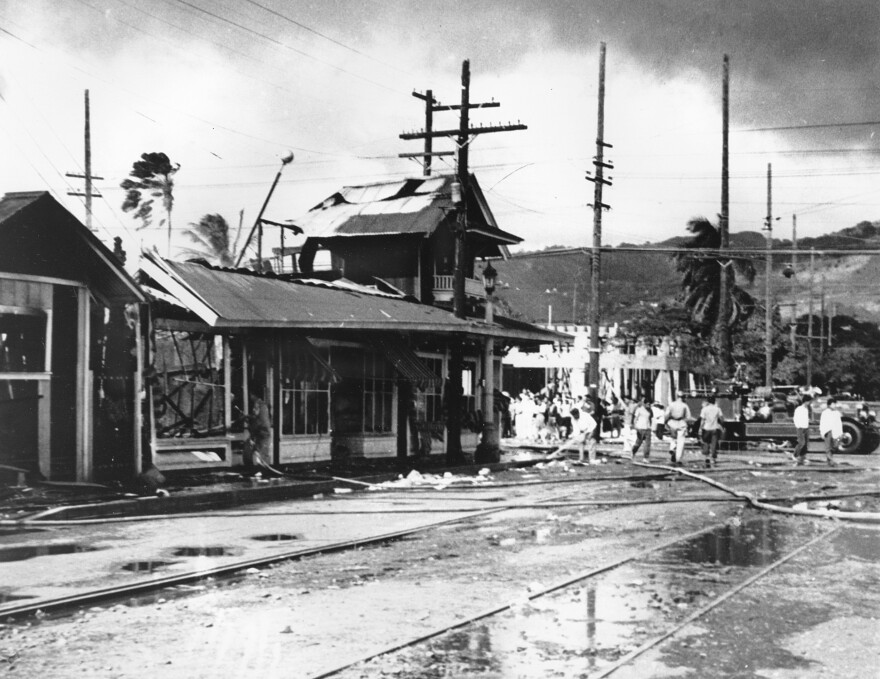 Firemen and civilians rush to the scene with fire hoses to save homes and stores in the Japanese and Chinese sections of Honolulu, Hawaiʻi, on Dec. 7, 1941. As Japanese aviators rained bombs on Pearl Harbor, starting war in the Pacific, offshore properties are also wrecked and burned. (AP Photo)