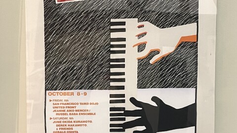 Close up of a poster on display. The poster reads "ASIAN AMERICAN JAZZ FESTIVAL" with a large cartoon graphic of two hands playing piano. 