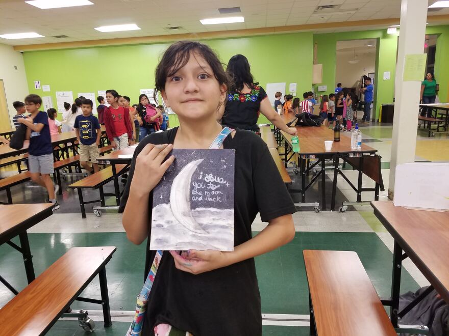 Luna Montez, 11, holds artwork inspired by her name, created at the MAS-LI camp.