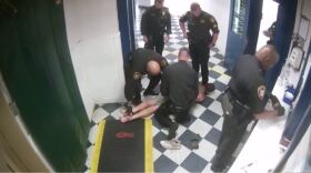 A screen grab of video footage showing the moments before Sgt. Franklin kicks the inmate in the head. Video shows the inmate, who had been standing on the marks to the left, kick backward before being wrestled to the ground by deputies.
