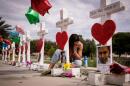 A woman writes a note on a cross for Eric Ivan Ortiz-Rivera at a memorial with wooden crosses for each of the 49 victims of the Pulse Nightclub, next to the Orlando Regional Medical Center, June 17, 2016 in Orlando, Florida. (Drew Angerer/Getty Images)