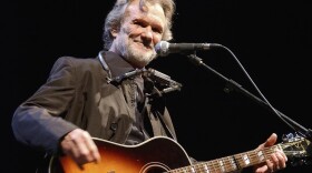 Kris Kristofferson playing guitar on stage.