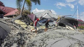 Men walk on a damaged road in the Petobo subdistrict on Tuesday, days after an earthquake and tsunami hit Palu in Central Sulawesi, Indonesia.