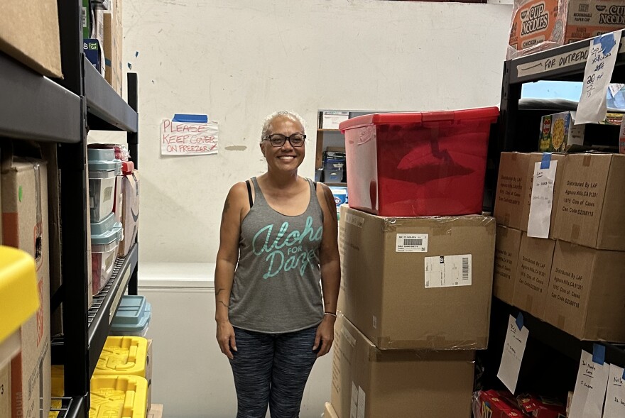 Trinette Furtado stands with stacks of supplies for fire survivors at Maui Rapid Response headquarters.