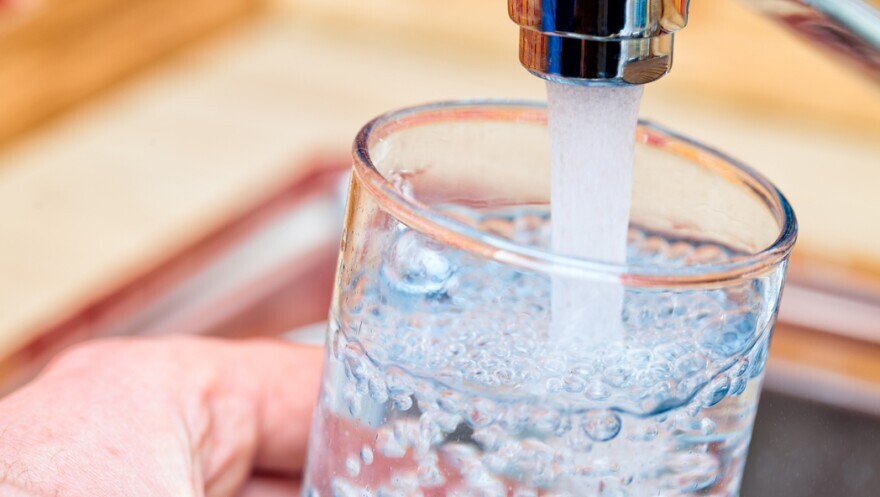 a glass of water under a running kitchen tap. 