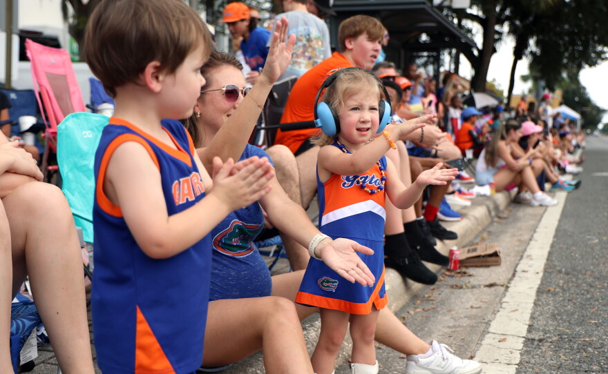 Clove Smith, right, gator chomps with her mother Keeley Smith, center, and family friends during the University of Florida Homecoming parade in Gainesville Friday, Oct. 9, 2026. (Taylin Huffman/WUFT News)
