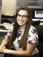 Lucia Starbuck is sitting next to a computer in the KUNR newsroom.