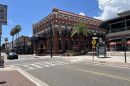 A street view of historic city district with brick buildings and paved streets with cars passing by.