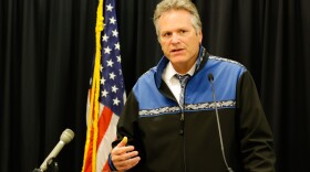 A man talks next to a flag.