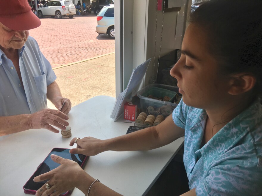 Brittany Touris gives a customer tokens to pay for produce at the Rochester Public Market after swiping his food stamp debit card.