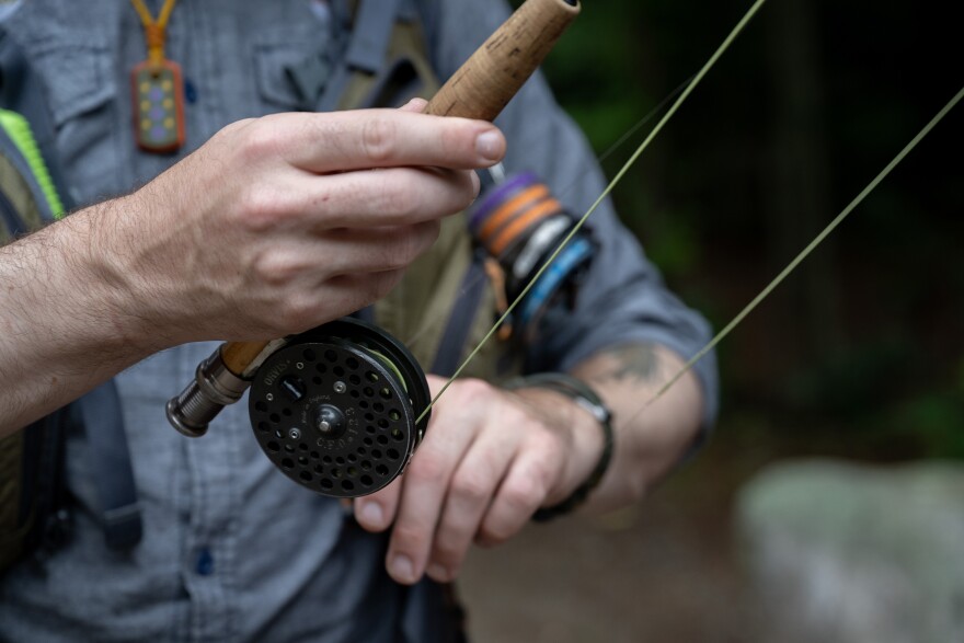 Fly fishing guide Geoff Klane prepares the antique reel on his rod as he gets ready to go fly fishing in Trap Falls on Thursday, Aug. 17, 2023, in northern Massachusetts. Klane crafts his own rods. (Raquel C. Zaldívar/New England News Collaborative)