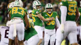 Players in football uniforms on a field where one is patting another on the chest.