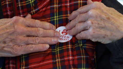 A voter puts on a sticker after casting their vote Tuesday, Nov. 4, 2025, at the Brighton Winter Farmers Market Barn.