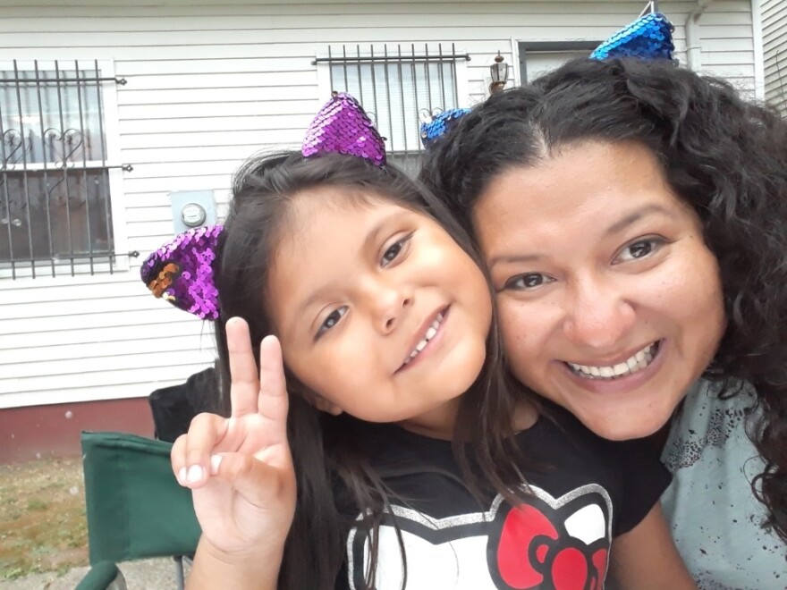 A young girl and her mother smile for a photo.