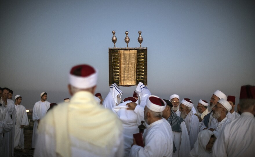 A priest lifts a Samaritan Torah scroll during sunrise prayers on Mount Gerizim in the West Bank. One of the world's oldest and tiniest sects, the Samaritans trace their roots to the ancient Israelites.