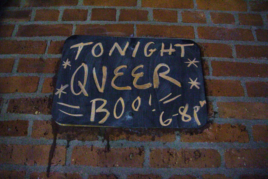 A chalkboard with orange chalk writing saying "Tonight Queer Boo! 6-8 pm"