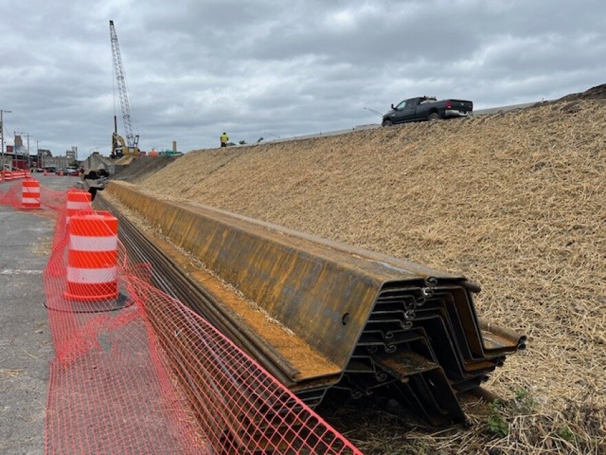 An access road leads to the crane installing pieces of a retaining wall for the Crouse Ave entrance ramp.