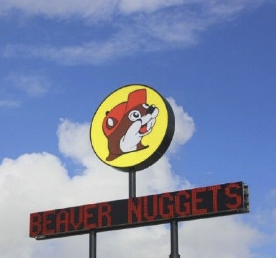 A circular yellow sign with a beaver wearing a hat atop a digital sign that reads "Beaver Nuggets."