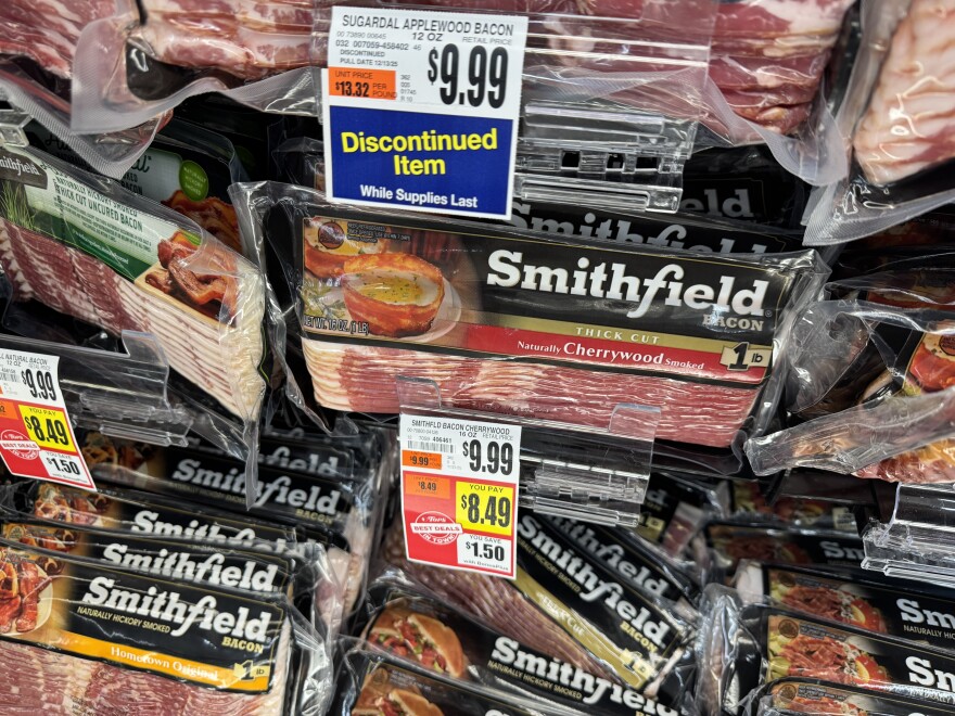 A grocery refrigerator bin filled with Smithfield bacon by the pound in thick cut, cherrywood smoke variety now costs $9.99.