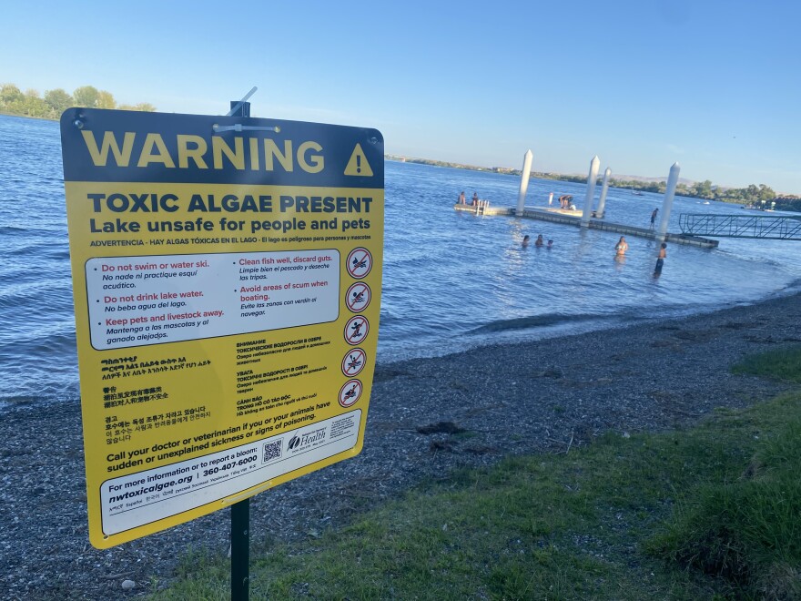 Children play recently at Howard Amon park in Richland, near a sign warning of toxic algae