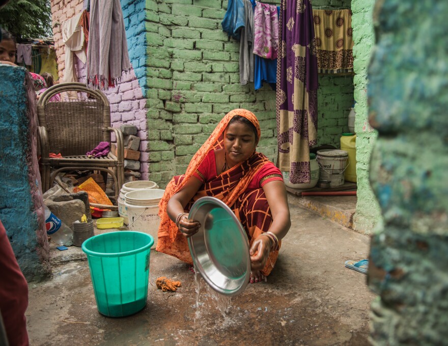 Shakuntala Devi, 26, a mother of three, washes dishes in the courtyard of her home in a crowded slum near the American Embassy School in New Delhi. Her home has no running water, so Devi has to fetch water in jerrycans from a government tanker truck.