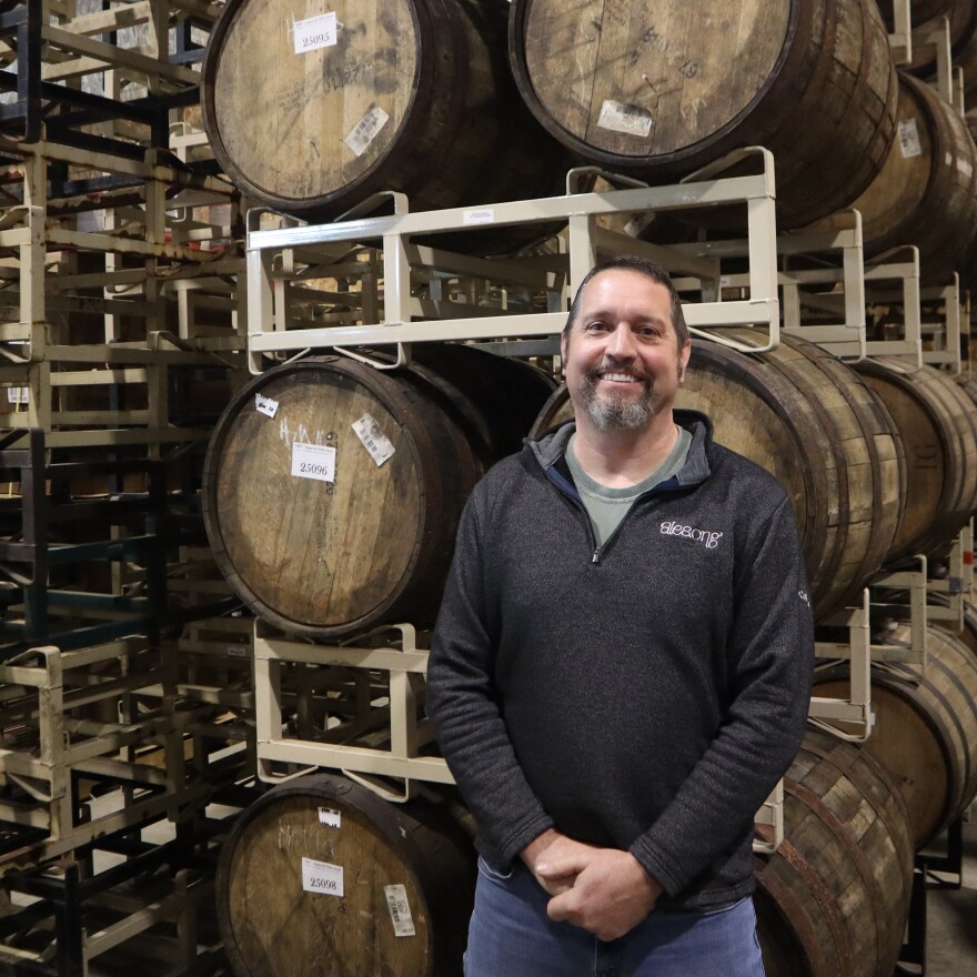 AleSong co-founder Matt Van Wyk standing in front of barrels.