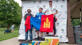 three men pose for pictures on medal podium at competition
