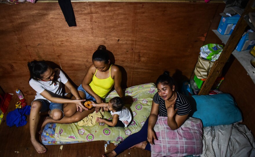 Baby Roseann plays with her two aunts and mother Rachel Quebec (far right) in their small house. Roseann's father, Clarence Jepadre, 17, was stabbed and killed last year. His body was found with a packet of marijuana and a note saying, "I'm a pusher... Don't be like me."