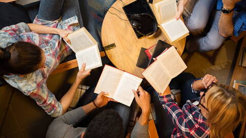Diverse group of friends discussing a book in library. Directly above.